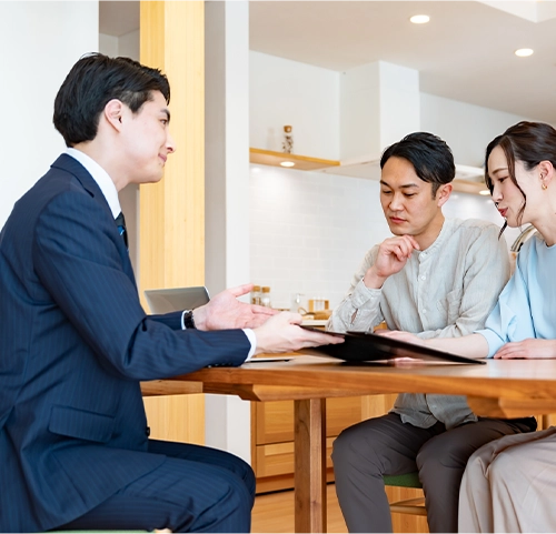 不動産担当者からの説明を聞く夫婦の写真